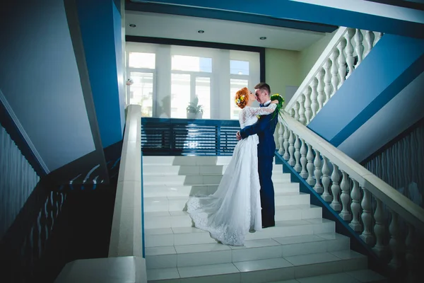 ブルーのスーツを着た若い美しいカップルとホテルの花束付きの白いウェディングドレス — ストック写真