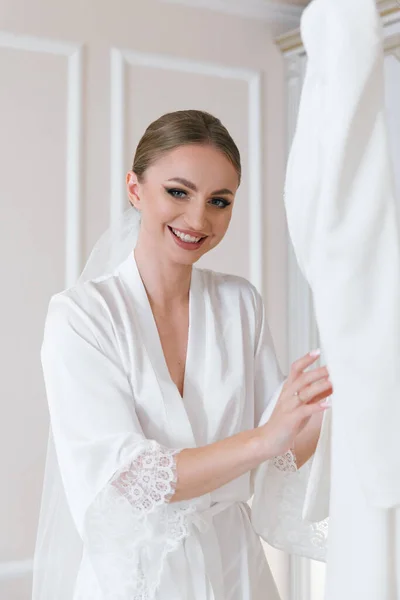 Fees for the wedding of a beautiful luxurious bride in a bathrobe with a wedding dress in a hotel, fashion portraits