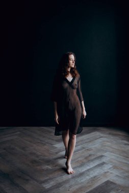 Beautiful, natural naked girl artistic posing at a stylish and fashionable nude photo shoot as a model in a photo studio with a transparent cape and bandage and looks like art