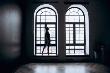 Beautiful, natural naked girl artistic posing at a stylish and fashionable nude photo shoot as a model in a photo studio with a transparent cape and bandage and looks like art