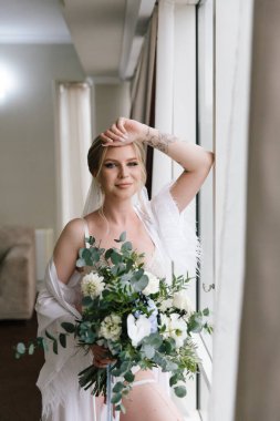 Güzelim, seksi bir gelinin iç çamaşırlı bir buketle sabah hazırlıkları. Bir otelde bornoz. Gelinlik giyip ayakkabılarını giydiği yer.