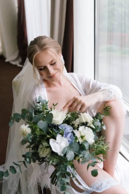 Güzelim, seksi bir gelinin iç çamaşırlı bir buketle sabah hazırlıkları. Bir otelde bornoz. Gelinlik giyip ayakkabılarını giydiği yer.