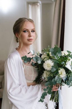 Güzelim, seksi bir gelinin iç çamaşırlı bir buketle sabah hazırlıkları. Bir otelde bornoz. Gelinlik giyip ayakkabılarını giydiği yer.