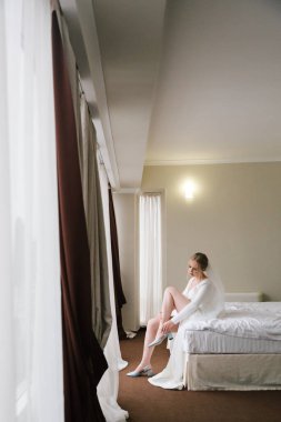 Güzelim, seksi bir gelinin iç çamaşırlı bir buketle sabah hazırlıkları. Bir otelde bornoz. Gelinlik giyip ayakkabılarını giydiği yer.