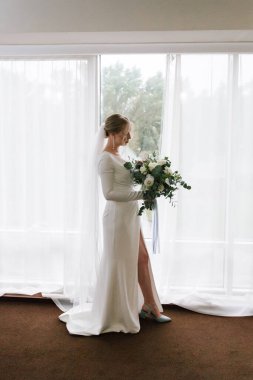 Güzelim, seksi bir gelinin iç çamaşırlı bir buketle sabah hazırlıkları. Bir otelde bornoz. Gelinlik giyip ayakkabılarını giydiği yer.