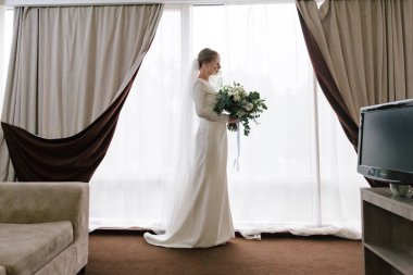 Güzelim, seksi bir gelinin iç çamaşırlı bir buketle sabah hazırlıkları. Bir otelde bornoz. Gelinlik giyip ayakkabılarını giydiği yer.