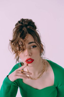 Güneş gözlüklü, ince vücutlu, mavi ceketli, yeşil elbiseli, şık, şık bir moda çekiminde fotoğraf stüdyosunda poz veren çekici bir kız..