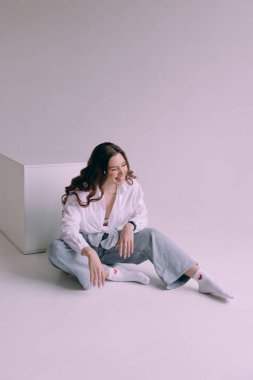 Güzel makyajlı, saç stili olan, kalıcı makyaj uzmanı, elinde aletler tutan lüks bir kız. Fotoğraf stüdyosunda takım elbiseli, kot pantolonlu ve gömlekli bir fotoğrafçı..