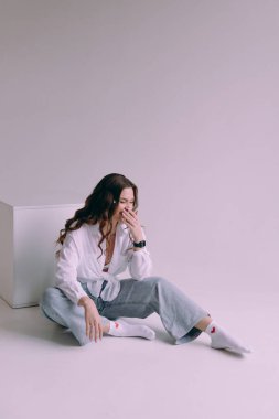 Güzel makyajlı, saç stili olan, kalıcı makyaj uzmanı, elinde aletler tutan lüks bir kız. Fotoğraf stüdyosunda takım elbiseli, kot pantolonlu ve gömlekli bir fotoğrafçı..