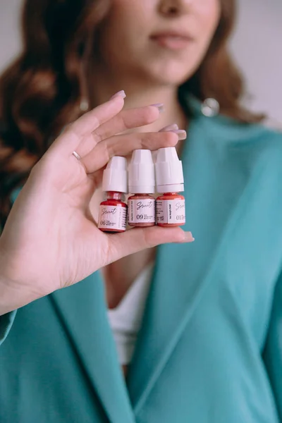 stock image Luxurious girl with beautiful makeup and hairstyle, permanent makeup specialist, holds tools in her hands. Photoshoot in a photo studio in a suit, jeans and a shirt.