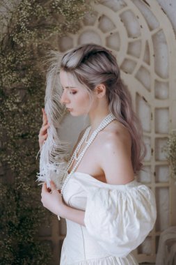 Kaliteli bir elbise içinde güzel bir makyajı ve saç stili olan lüks bir kız bir sabah yatağında uyanıp piyanonun yanındaki kanepede modellik yapıyor.