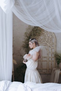 Kaliteli bir elbise içinde güzel bir makyajı ve saç stili olan lüks bir kız bir sabah yatağında uyanıp piyanonun yanındaki kanepede modellik yapıyor.