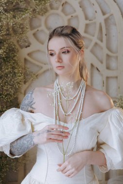 Kaliteli bir elbise içinde güzel bir makyajı ve saç stili olan lüks bir kız bir sabah yatağında uyanıp piyanonun yanındaki kanepede modellik yapıyor.