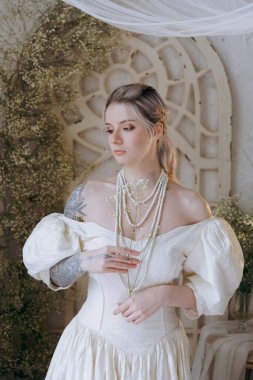 Kaliteli bir elbise içinde güzel bir makyajı ve saç stili olan lüks bir kız bir sabah yatağında uyanıp piyanonun yanındaki kanepede modellik yapıyor.