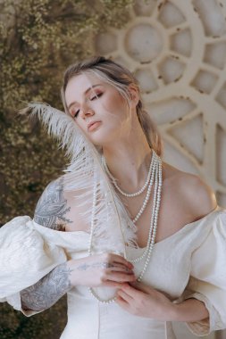 Kaliteli bir elbise içinde güzel bir makyajı ve saç stili olan lüks bir kız bir sabah yatağında uyanıp piyanonun yanındaki kanepede modellik yapıyor.