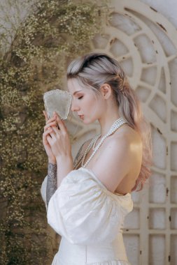 Kaliteli bir elbise içinde güzel bir makyajı ve saç stili olan lüks bir kız bir sabah yatağında uyanıp piyanonun yanındaki kanepede modellik yapıyor.