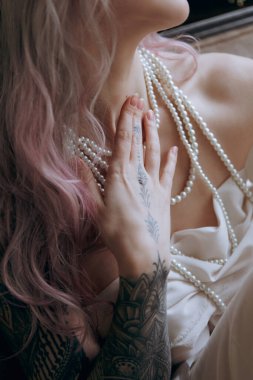 Kaliteli bir elbise içinde güzel bir makyajı ve saç stili olan lüks bir kız bir sabah yatağında uyanıp piyanonun yanındaki kanepede modellik yapıyor.