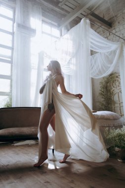 Kaliteli bir elbise içinde güzel bir makyajı ve saç stili olan lüks bir kız bir sabah yatağında uyanıp piyanonun yanındaki kanepede modellik yapıyor.