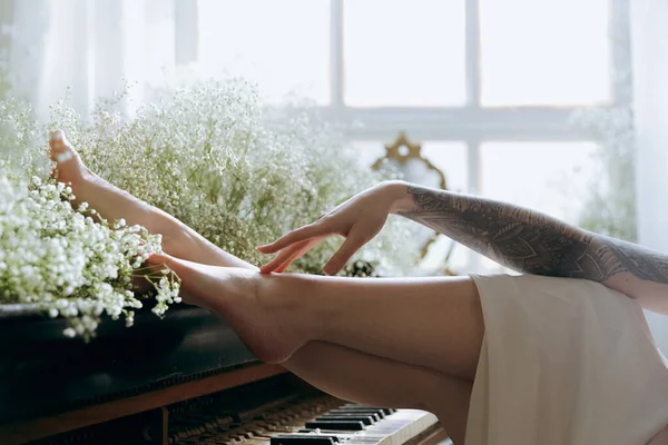 一个穿着老式衣服 化着漂亮妆容和发型的奢华女孩在床上醒来 坐在钢琴旁边的沙发上 摆出一副模特的模样 — 图库照片