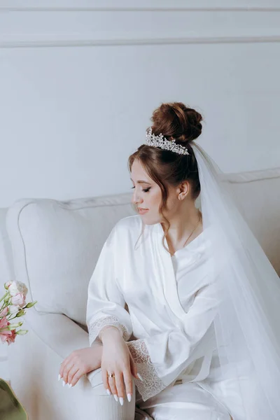 美しいの朝の準備 バルコニーのバスローブでセクシーな花嫁とソファ 彼女は結婚式のドレスに靴を着る場所 — ストック写真
