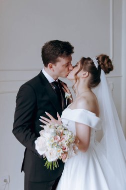 Damadın siyah takım elbiseli ilk buluşması ve beyaz gelinlikli gelinin beyaz ve siyah arka planda bir fotoğraf stüdyosunun içinde bir buket olması.