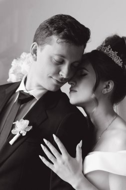Damadın siyah takım elbiseli ilk buluşması ve beyaz gelinlikli gelinin beyaz ve siyah arka planda bir fotoğraf stüdyosunun içinde bir buket olması.