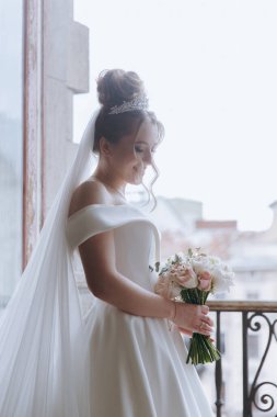 Balkonda ve kanepede bornozlu güzel, seksi bir gelinin sabah hazırlıkları.