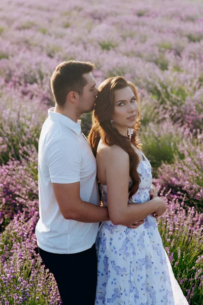 A beautiful couple, where a girl in a chic dress on a lavender field at sunset.