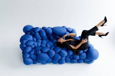 Fotoğraf stüdyosundaki lüks, seksi ve güzel bir kız siyah pantolon giyip şık bir şekilde poz veriyor.