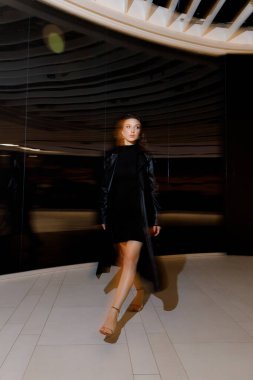 Kısa elbiseli ve deri ceketli güzel bir manken, bir moda şehrinin fotoğraf çekiminde poz veriyor, şehirde dolaşıyor..