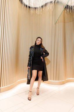 Kısa elbiseli ve deri ceketli güzel bir manken, bir moda şehrinin fotoğraf çekiminde poz veriyor, şehirde dolaşıyor..