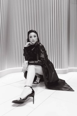 Kısa elbiseli ve deri ceketli güzel bir manken, bir moda şehrinin fotoğraf çekiminde poz veriyor, şehirde dolaşıyor..