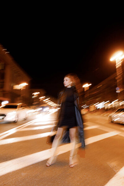 A beautiful model in a short dress and a leather trench coat, posing at a fashion city photo shoot, walking around the city.