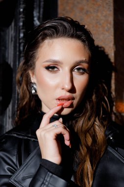 Kısa elbiseli ve deri ceketli güzel bir manken, bir moda şehrinin fotoğraf çekiminde poz veriyor, şehirde dolaşıyor..