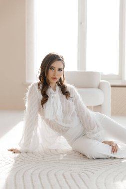 Fotoğraf stüdyosundaki fotoğraf çekiminde makyaj ve saç stili olan seksi, lüks bir kız. O güzel ve şık bir şekilde kırmızı bir elbise, çoraplar, bir buket çiçek ve güllerle poz verdi..