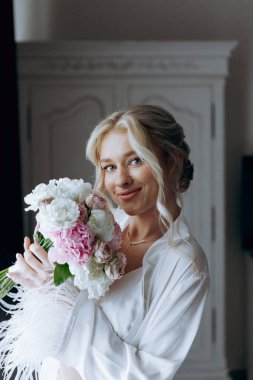 Gelinin sabahı, şık saçlı ve makyajlı bir bornozla güzel lüks bir otelde düğüne hazırlanır ve sonra beyaz bir gelinlik giyer..