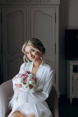 Gelinin sabahı, şık saçlı ve makyajlı bir bornozla güzel lüks bir otelde düğüne hazırlanır ve sonra beyaz bir gelinlik giyer..