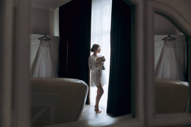 Gelinin sabahı, şık saçlı ve makyajlı bir bornozla güzel lüks bir otelde düğüne hazırlanır ve sonra beyaz bir gelinlik giyer..