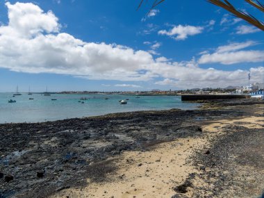 Corralejo Körfezi 'nde tekneler, sörf okulları, evler ve arka planda dağlar, İspanya