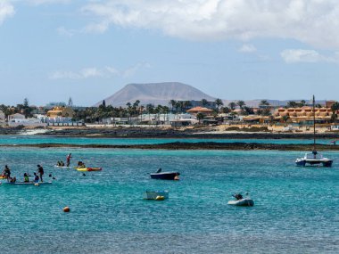 Corralejo Körfezi 'nde tekneler, sörf okulları, evler ve arka planda dağlar, İspanya