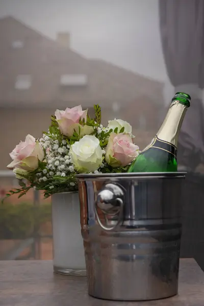 Rose bush and champagne cooler with open champagne bottle