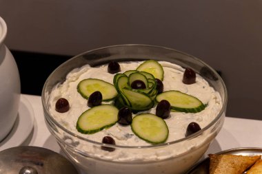 Salatalık ve zeytinle süslenmiş cam bir kasede Tzatziki