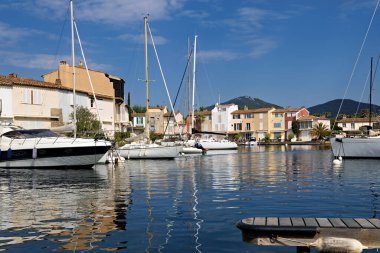 Grimaud Limanı 'nda gemiler, yatlar, rıhtımlar, dükkanlar ve konut binaları var.