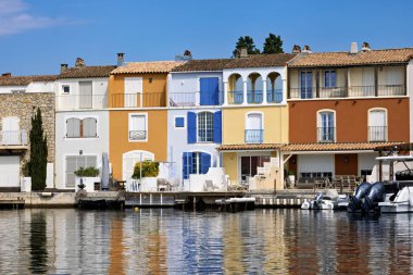 Grimaud Limanı 'nda gemiler, yatlar, rıhtımlar, dükkanlar ve konut binaları var.