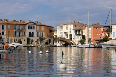 Grimaud Limanı 'nda gemiler, yatlar, rıhtımlar, dükkanlar ve konut binaları var.