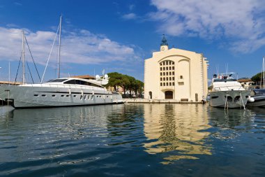 Fransa 'nın Port Grimaud şehrinde baharda kafeler, restoranlar, yatlar, kilise ve yelkenliler