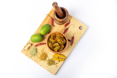 Ahşap zemin üzerinde ahşap havan ve yeşil mango ve baharatlarla mango turşusu.