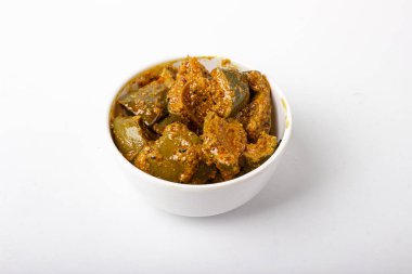 Beyaz arka planda beyaz seramik kasede baharatlı mango turşusu.