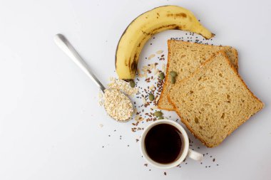 Balkabağı, chia, keten tohumu, muz, sade kahve ve beyaz arka planda yulaf ezmeli sağlıklı ve lezzetli çoklu tahıllı ekmek.