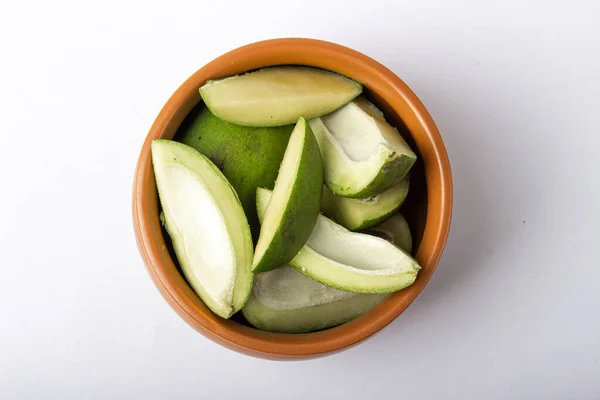 green mangoes slices for pickle in brown bowl